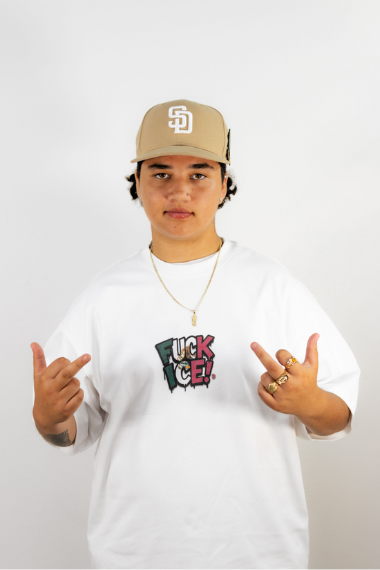 Person wearing a white sweatshirt with a logo and a beige cap on a plain background